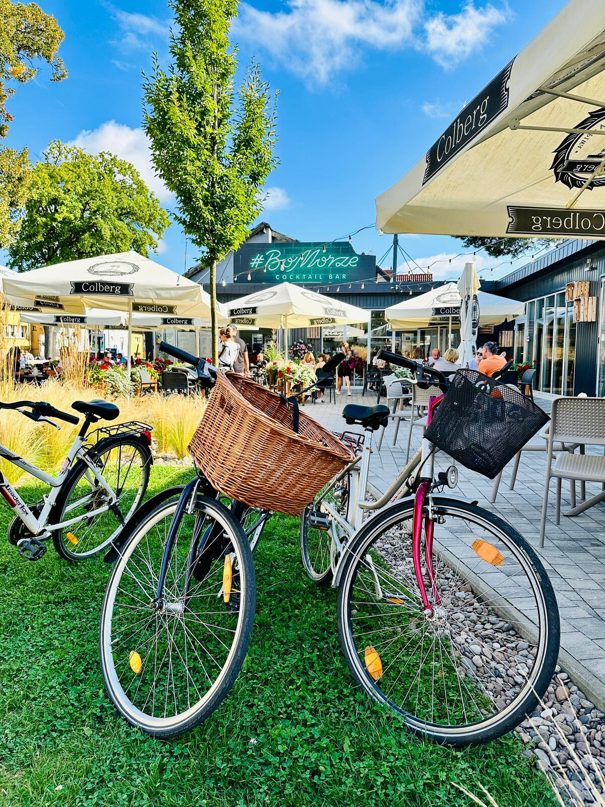 BoMorze garden — bikes with baskets, Colberg parasols, #BoMorze Cocktail Bar neon sign