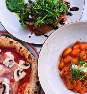 Three BoMorze plates from above — Capriciosa pizza, gnocchi al pomodoro, burrata salad
