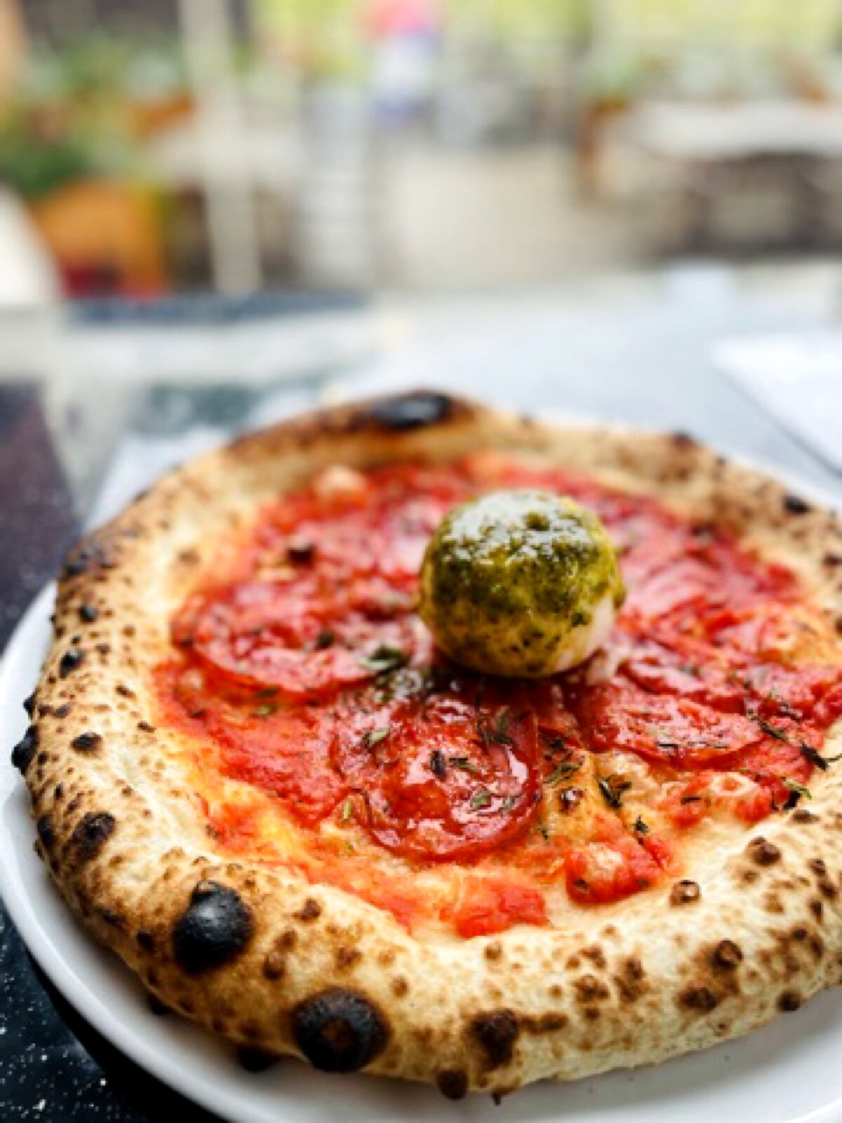 Pizza with salami and a mozzarella ball with basil pesto