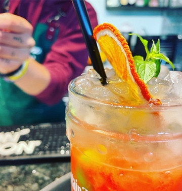 Oranger Cocktail mit getrockneter Orangenscheibe und Minze