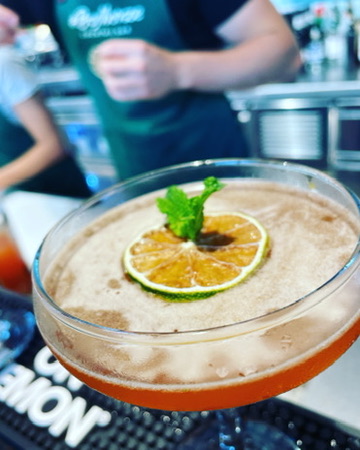 Whiskey Sour mit Zitronenscheibe und Minzzweig auf der Bar Mat