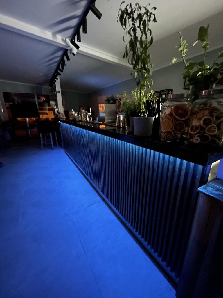 BoMorze Bar bei Nacht — blaues LED, Gläser mit getrockneten Zitrusfrüchten