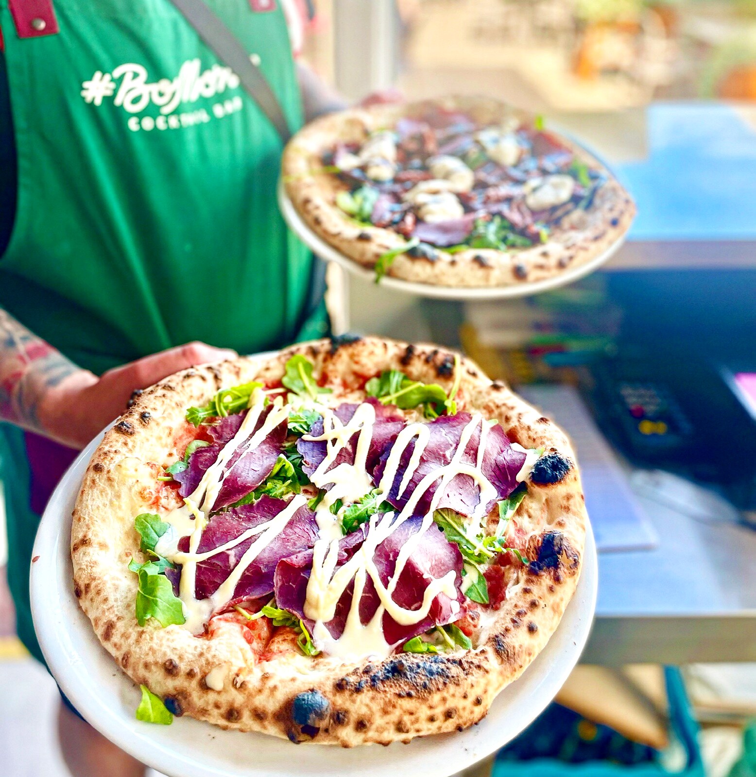 #BoMorze Cocktail Bar waiter serving two pizzas — bresaola with arugula