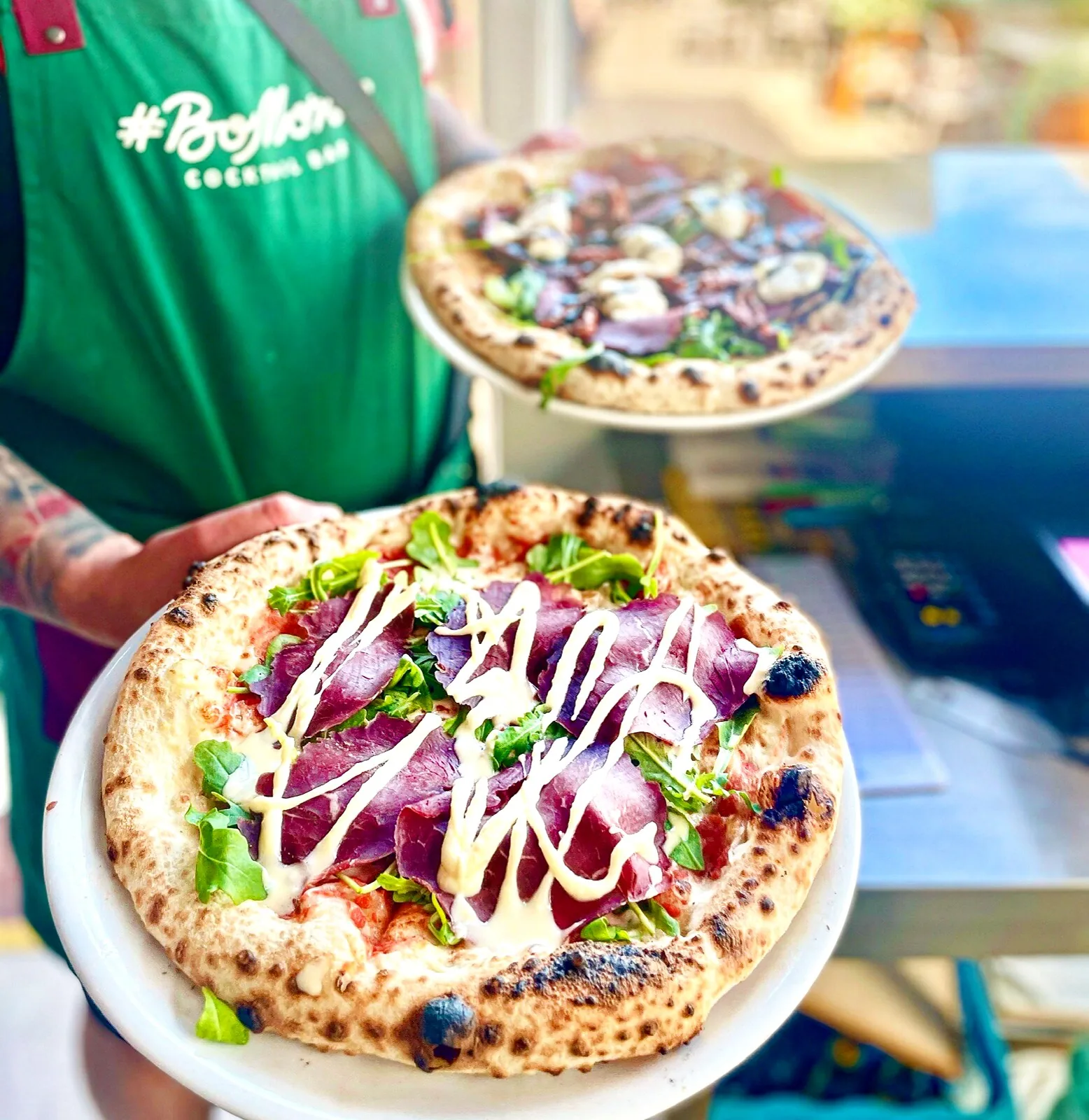 BoMorze waiter serving two pizzas — bresaola with arugula